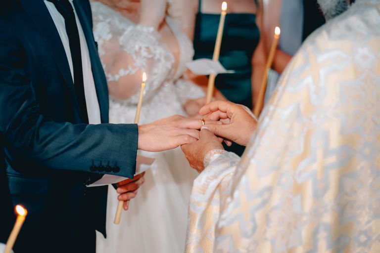 A couple exchanges rings during a traditional wedding ceremony in a church setting.